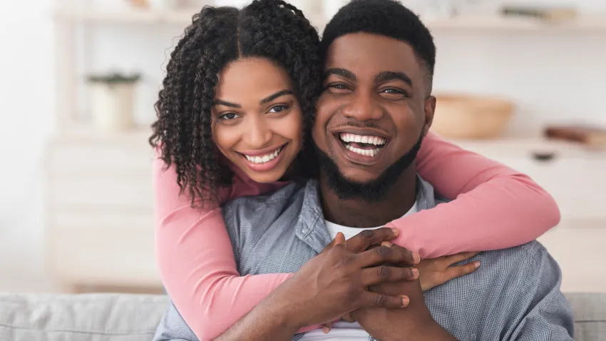 Stock photo of woman smiling wrapping arms around man smiling